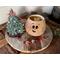 This is Fraser the Elf with his hat off, placed next to him. You can see the inside of the gourd is unfinished. Jingle bells lay nearby. 